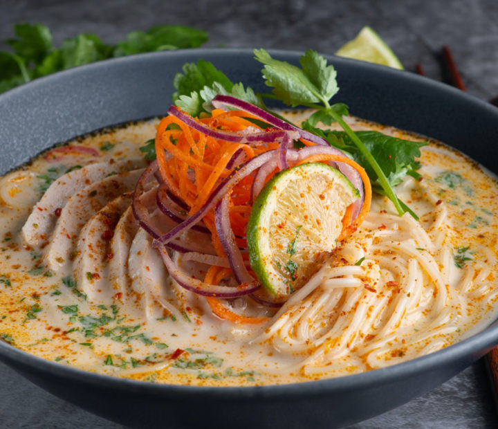 Noodle soup garnished with lime, carrots, onions and coriander leaves.